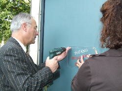 Wethouder Henk v Hooft schroeft naamplaat van de jeugdsoos op de deur